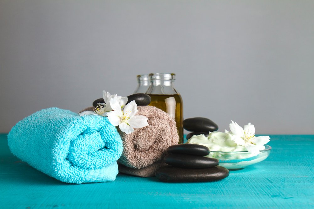 a towel and towels with flowers and a bowl of cream and black stones